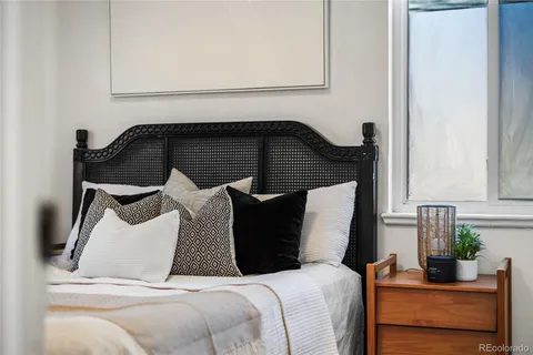 a bedroom with a bed and a potted plant on the dresser