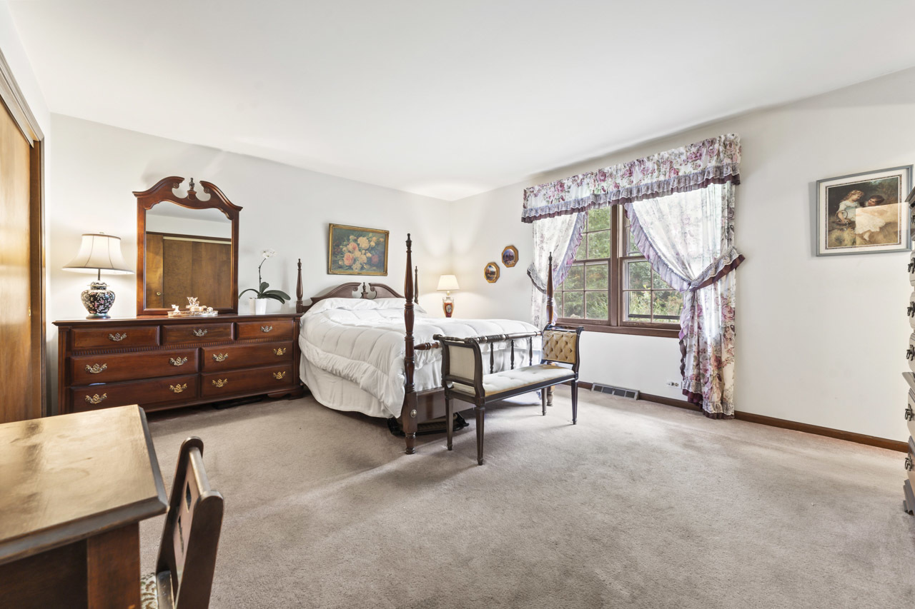 245 Bradwell Road Inverness, IL 60010 - Photo 21 of 43 a spacious bedroom with a bed a table and painting on the wall