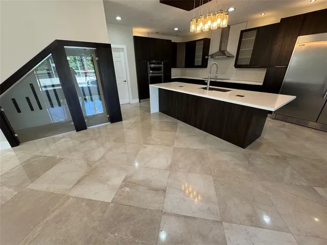 a large white kitchen with a large counter top and stainless steel appliances