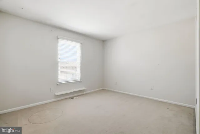 an empty room with chandelier fan and windows