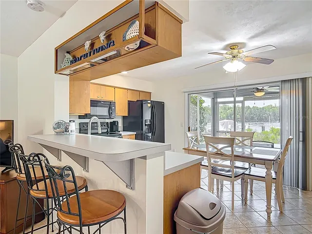 a kitchen with stainless steel appliances kitchen island granite countertop a refrigerator a stove top oven a sink with dining table and chairs