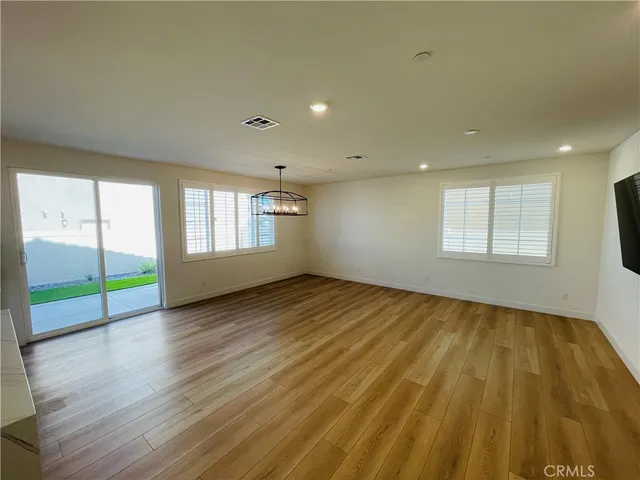 a view of an empty room with kitchen and window