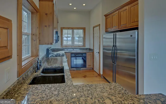 an empty room with wooden floor chandelier fan and windows