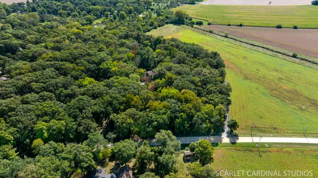 an aerial view of a residential houses with outdoor space and trees all around