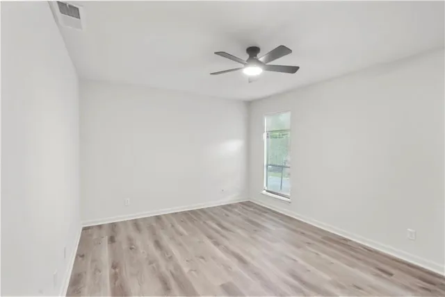 an empty room with windows and fan