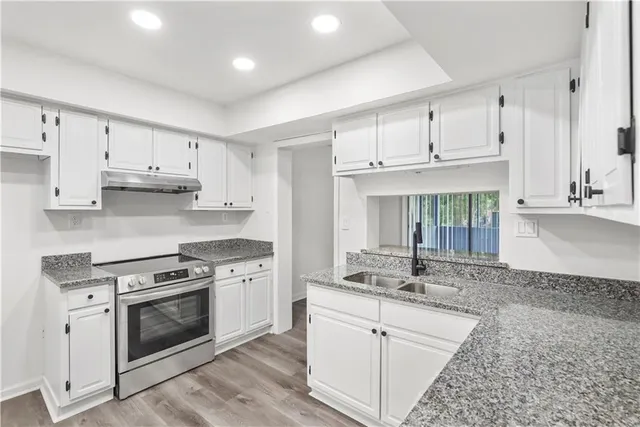 a kitchen with granite countertop a stove top oven sink and cabinets