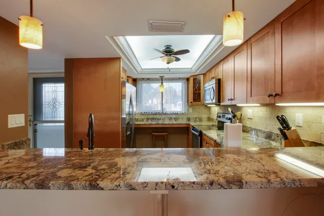 a kitchen with stainless steel appliances granite countertop sink stove refrigerator and cabinets