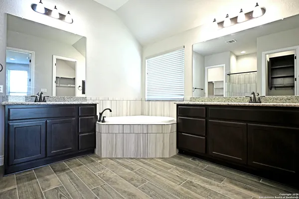 a bathroom with a granite countertop double vanity sink and mirror