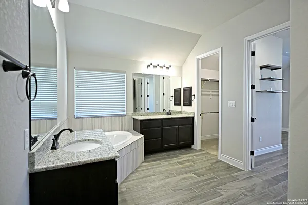 a large bathroom with a granite countertop sink a mirror and shower