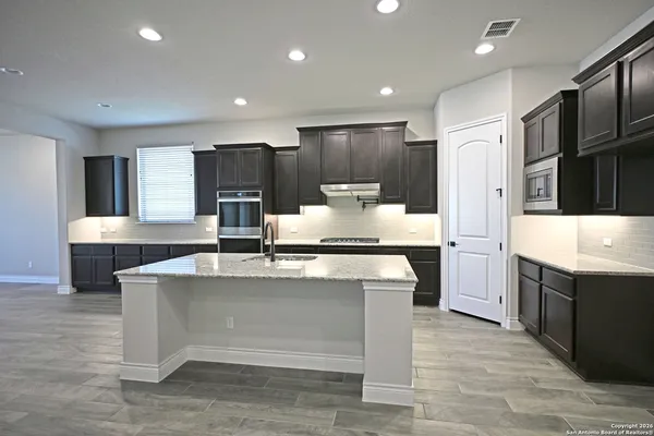 a large kitchen with kitchen island a sink a stove a refrigerator and white cabinets