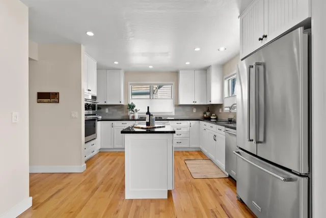 a kitchen with white cabinets stainless steel appliances and a refrigerator