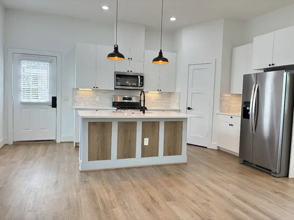 a kitchen with stainless steel appliances granite countertop a sink a stove a refrigerator and a microwave