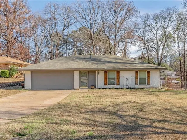 a front view of a house with yard and trees