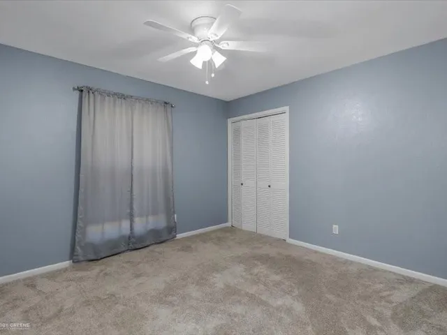 an empty room with a chandelier fan and entryway