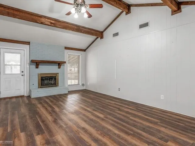 a view of an empty room with a fireplace and a window