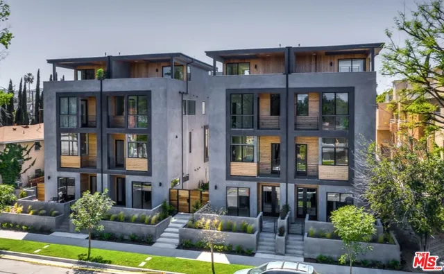 a front view of a brick building with many windows and yard