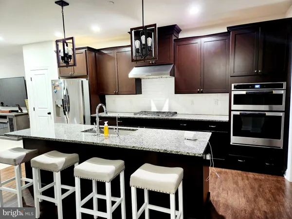 a kitchen with stainless steel appliances kitchen island granite countertop a table chairs and a refrigerator