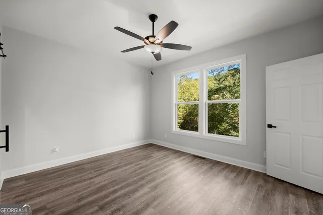 a view of empty room with wooden floor and fan