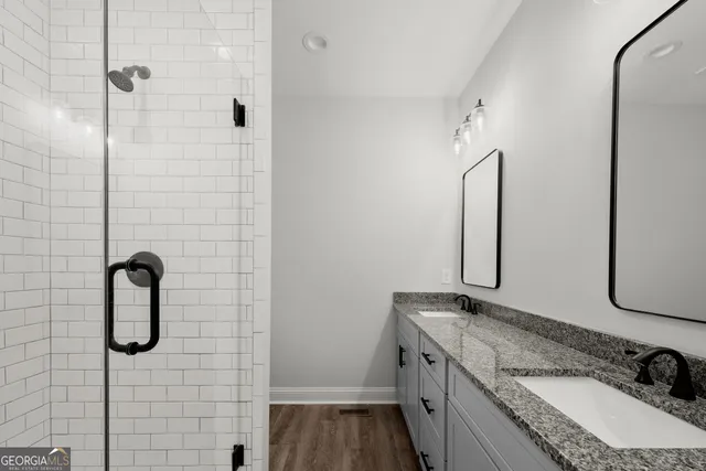 a bathroom with a granite countertop sink a mirror and shower