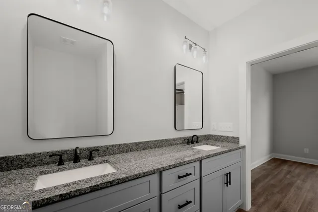 a bathroom with a granite countertop double vanity sink and a mirror