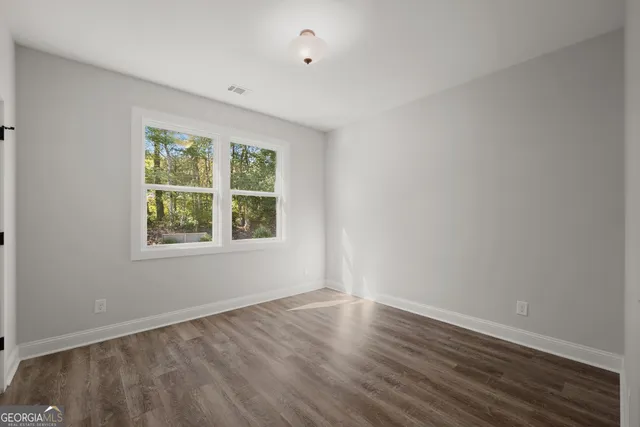 a view of an empty room with wooden floor and a window