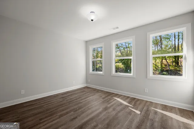 a view of an empty room with wooden floor and windows