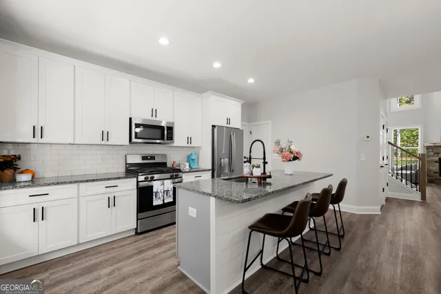 a kitchen with white cabinets stainless steel appliances and dining table