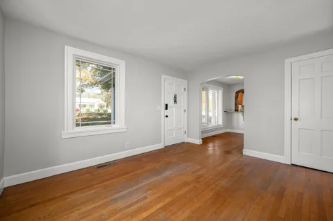 a view of an empty room with wooden floor and a window