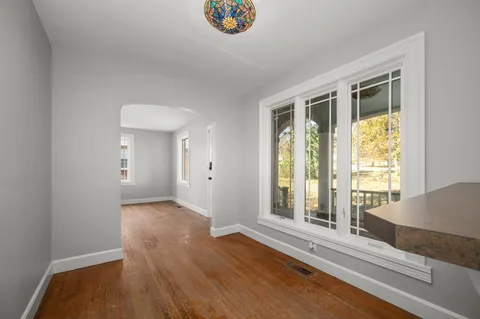 a view of an empty room with wooden floor and a window