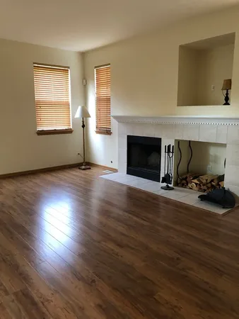 a view of a livingroom with wooden floor fireplace and a window