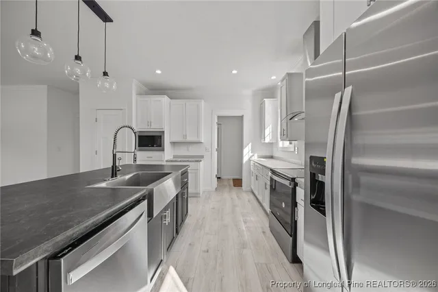 a kitchen with kitchen island a counter top space a sink stainless steel appliances and cabinets