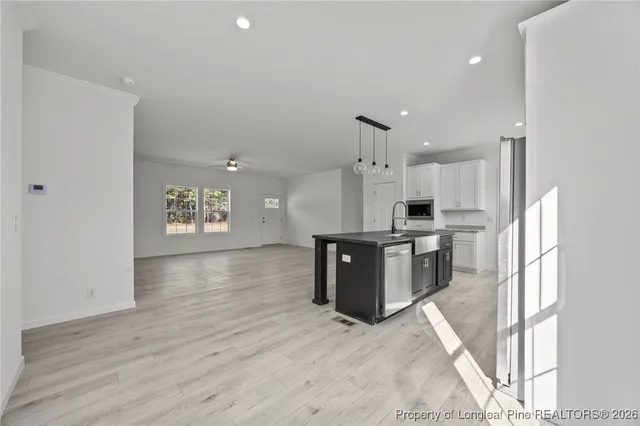 a kitchen with stainless steel appliances kitchen island granite countertop a refrigerator a sink dishwasher a stove with wooden cabinets and floor