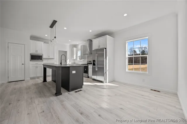 a open kitchen with stainless steel appliances granite countertop a stove a sink dishwasher and a refrigerator with wooden floor