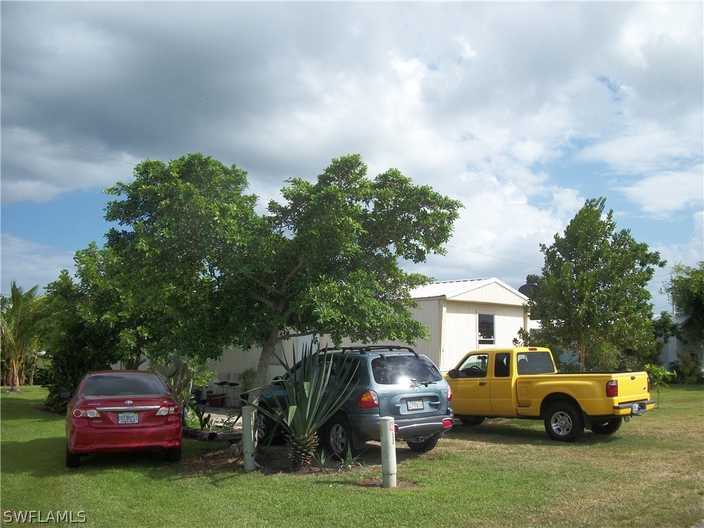 1002-1009 Nalls Road Clewiston, FL 33440 - Photo 16 of 19 a car parked in front of a house with a garden