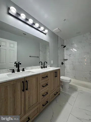 a spacious bathroom with a double vanity sink a toilet and a shower