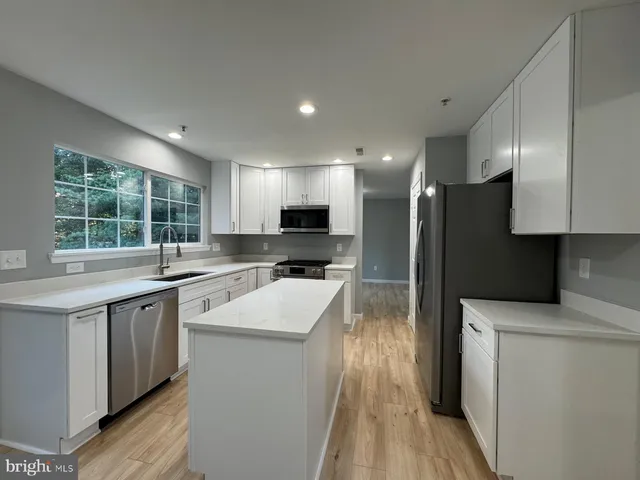 a kitchen with stainless steel appliances granite countertop a sink stove refrigerator and cabinets