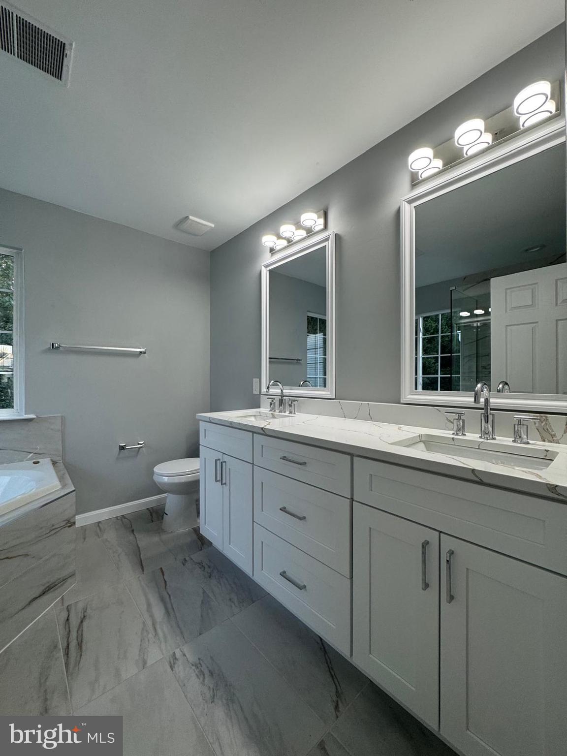 16107 Eckhart Road Bowie, MD 20716 - Photo 10 of 18 a spacious bathroom with a double vanity sink a toilet and a mirror