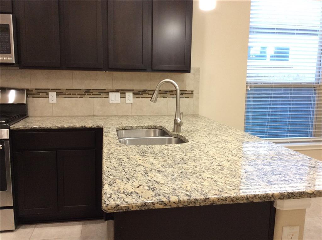 3451 Mayfield Ranch Boulevard, Unit 340 Round Rock, TX 78681 - Photo 5 of 13 Ample granite counters and sleek dark cabinetry define this modern kitchen.