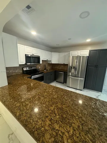 a kitchen with granite countertop a refrigerator and a stove top oven
