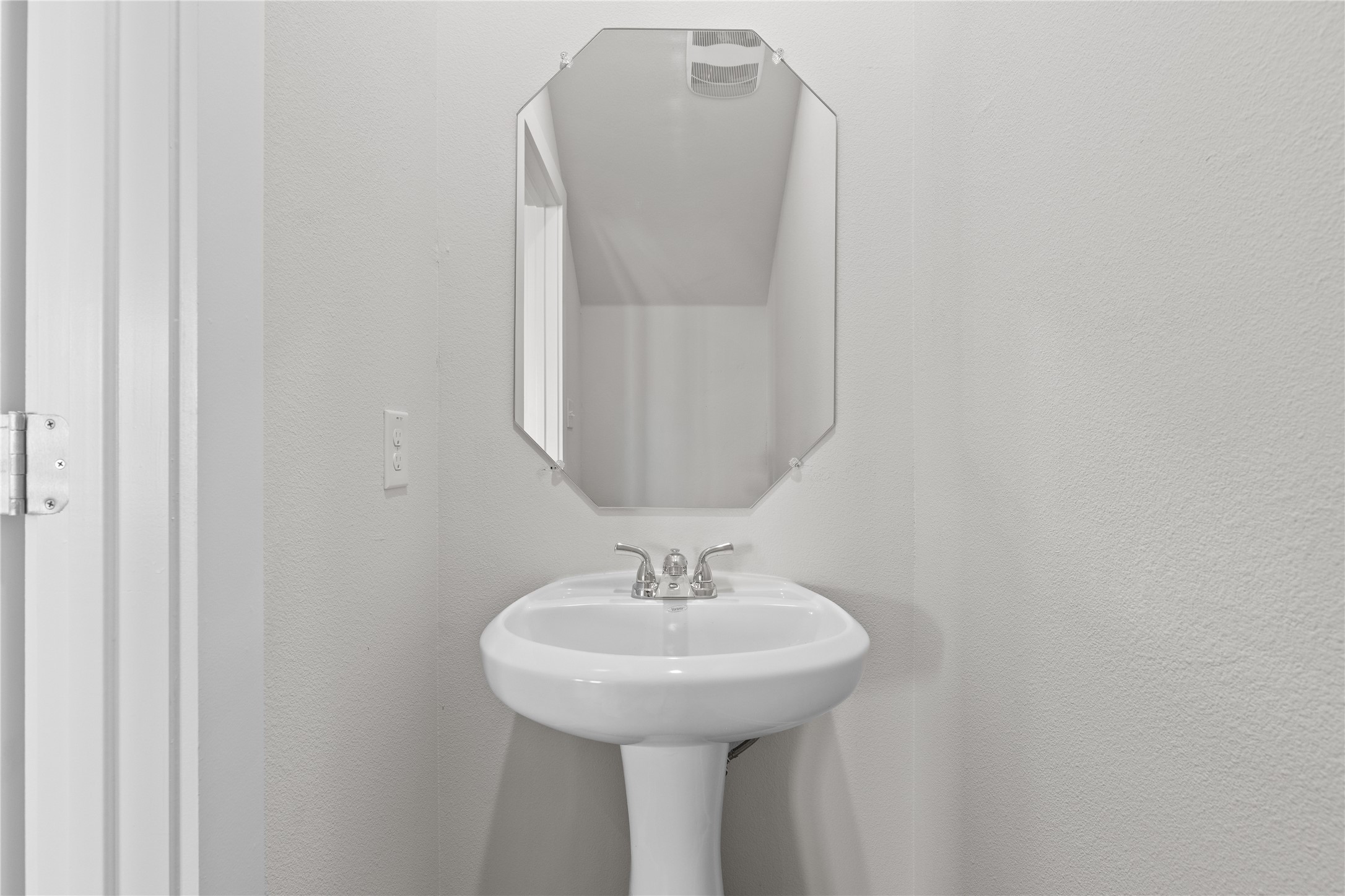 19705 Domino Champ Road Pflugerville, TX 78660 - Photo 10 of 38 A classic pedestal sink sits below a geometric wall mirror in this powder room.