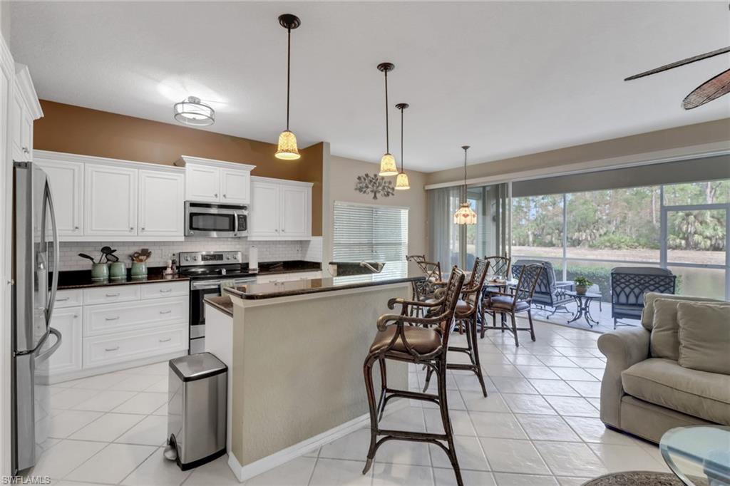 5325 Andover Drive, Unit 101 Naples, FL 34110 - Photo 8 of 25 Kitchen with plenty of natural light, white cabinetry, hanging light fixtures, and appliances with stainless steel finishes