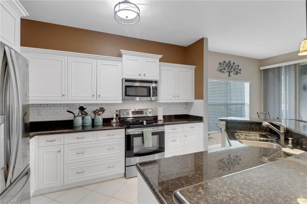 5325 Andover Drive, Unit 101 Naples, FL 34110 - Photo 9 of 25 Kitchen featuring appliances with stainless steel finishes, tasteful backsplash, white cabinetry, and sink