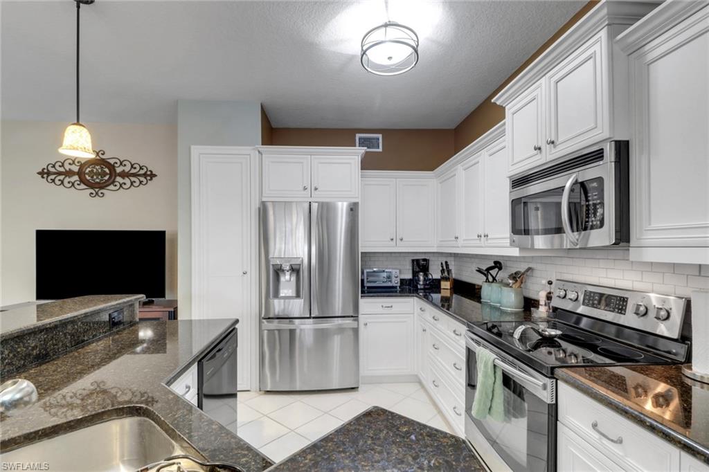5325 Andover Drive, Unit 101 Naples, FL 34110 - Photo 10 of 25 Kitchen with appliances with stainless steel finishes, backsplash, white cabinetry, and dark stone counters