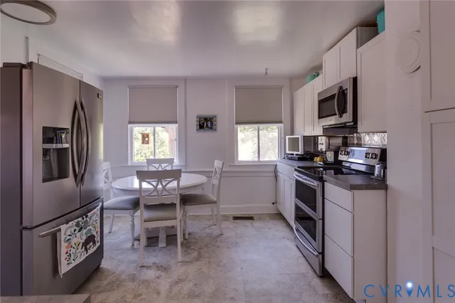 a kitchen with stainless steel appliances granite countertop a stove top oven a sink dishwasher a dining table and chairs with wooden floor