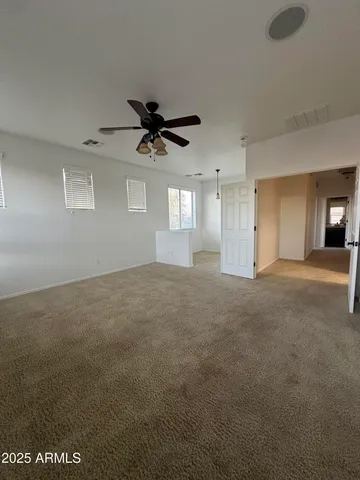 a view of a big room with a ceiling fan and windows