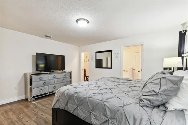 a spacious bedroom with a bed and a flat screen tv
