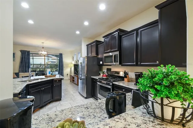 a kitchen with granite countertop a table chairs microwave and refrigerator