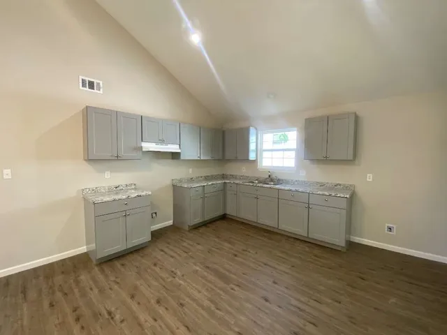 a kitchen with a white cabinets and wooden floor