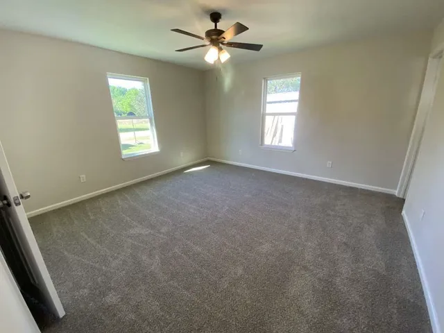 an empty room with windows and fan
