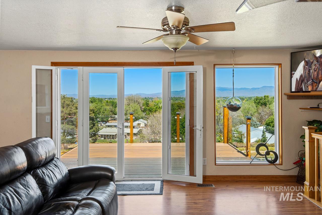 10178 West Fox Ridge Drive Boise, ID 83709 - Photo 3 of 36 Living area featuring a ceiling fan, wood-finish flooring, and multi-panel glass doors opening to an exterior deck